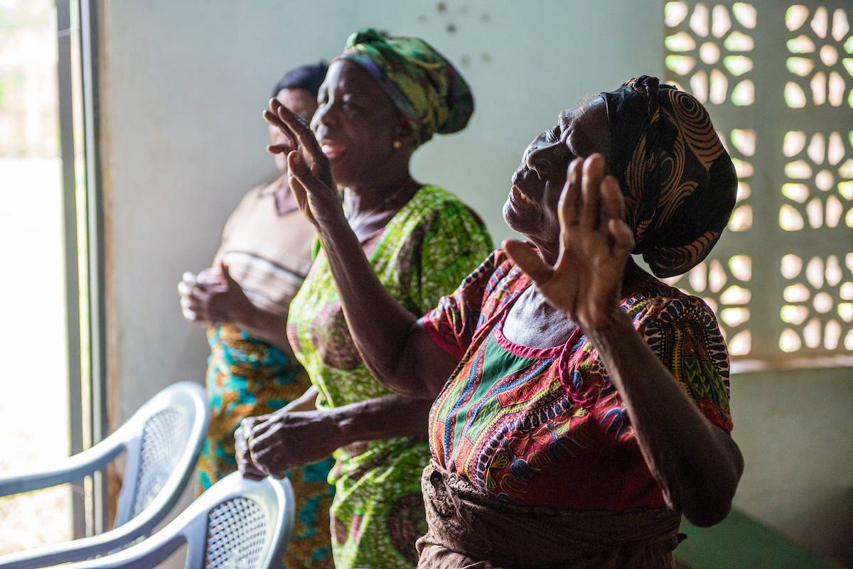 Three Ghanaian women worshipping in church.
